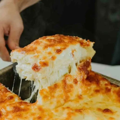 Scooping a cheesy slice of ground beef and potato cowboy casserole