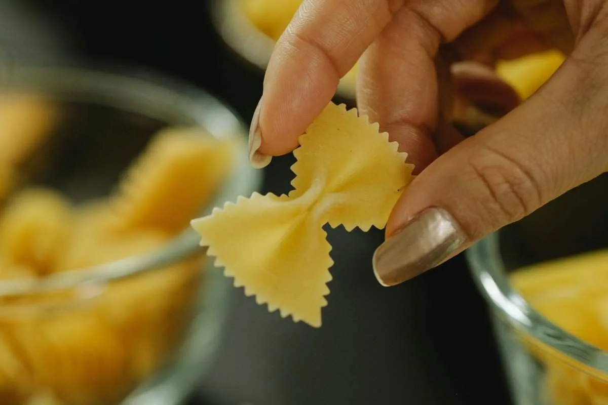Holding a piece of dry bowtie pasta for crockpot recipe