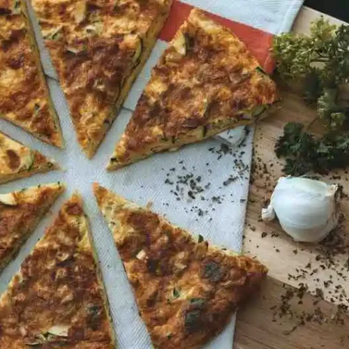 Sliced crispy hash brown breakfast pizza served on a wooden board