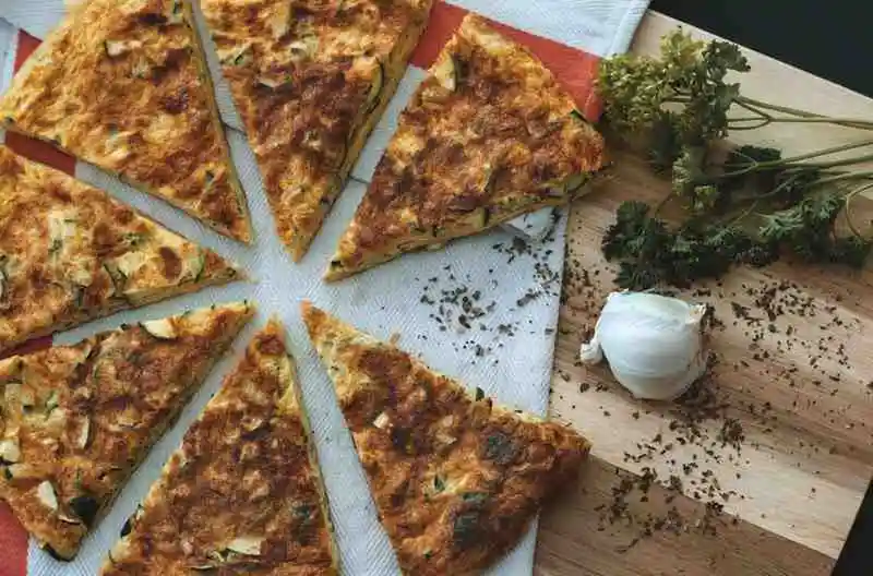 Sliced crispy hash brown breakfast pizza served on a wooden board