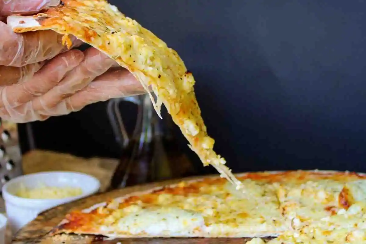 A slice of cheesy hash brown breakfast pizza with melted cheese pull