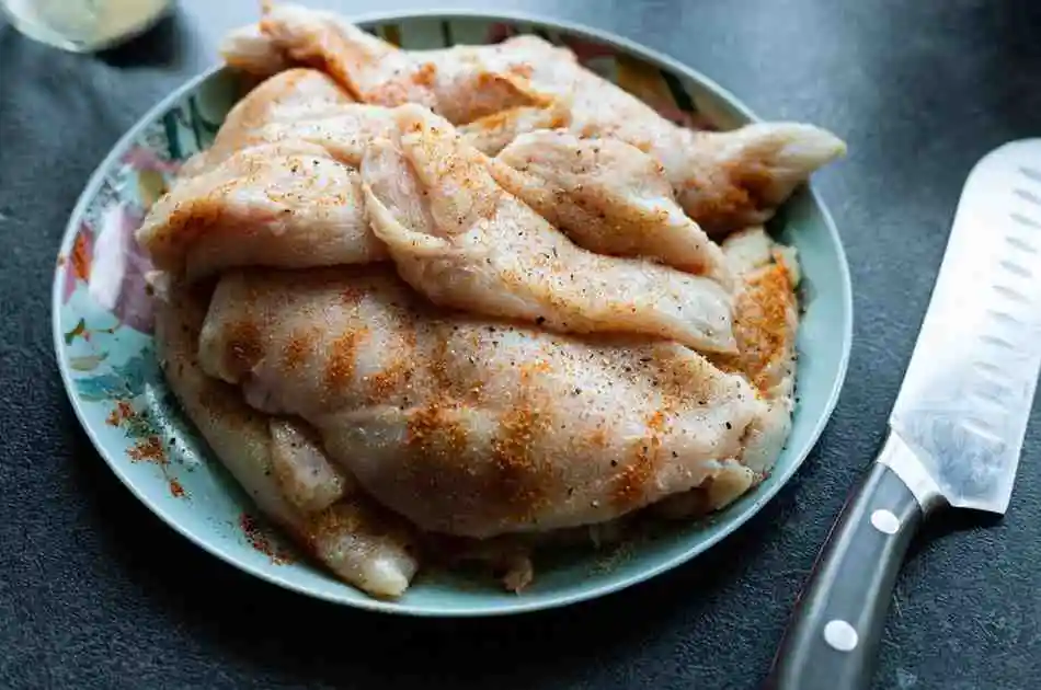 Raw chicken tenders coated in Greek yogurt and lemon herb marinade