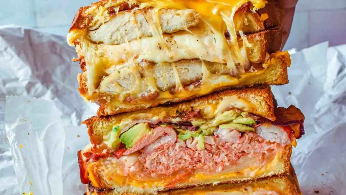 Grilled chicken avocado melt sandwich with melted cheese sliced in half