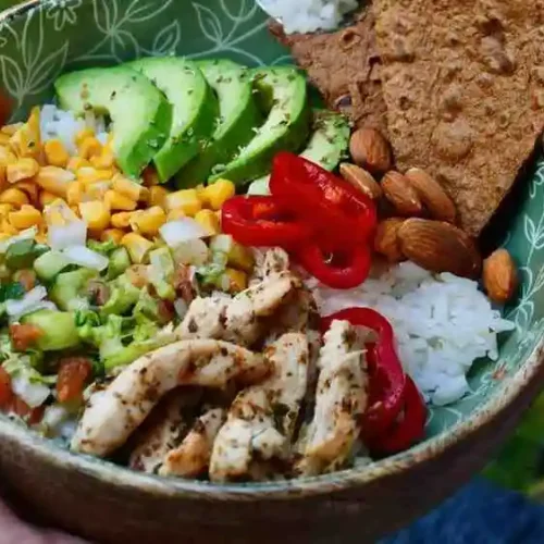 Freshly served grilled chicken avocado bowl with fresh cilantro and toppings