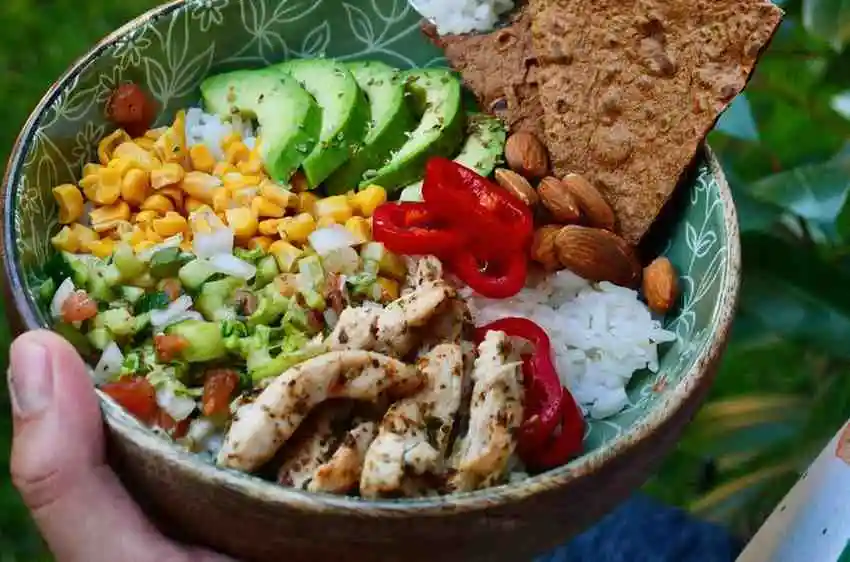 Freshly served grilled chicken avocado bowl with fresh cilantro and toppings