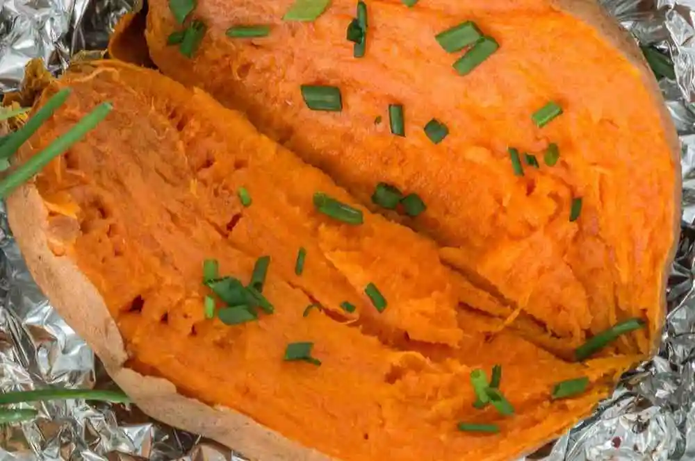 Baked sweet potato sliced open before filling for boats