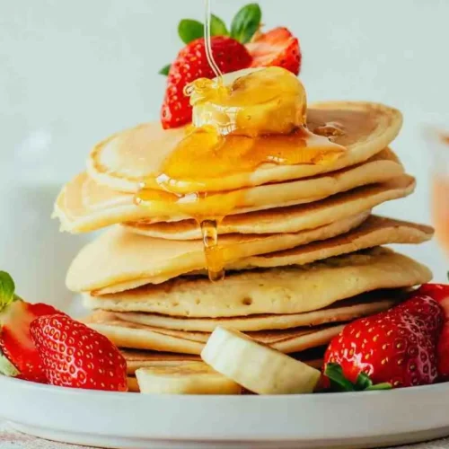 Sweet pancake breakfast tacos topped with fresh strawberries blueberries and maple syrup