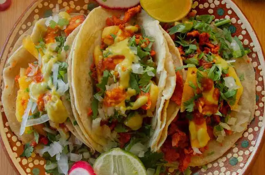 Loaded pineapple chicken tacos topped with fresh cilantro, cheese, and lime
