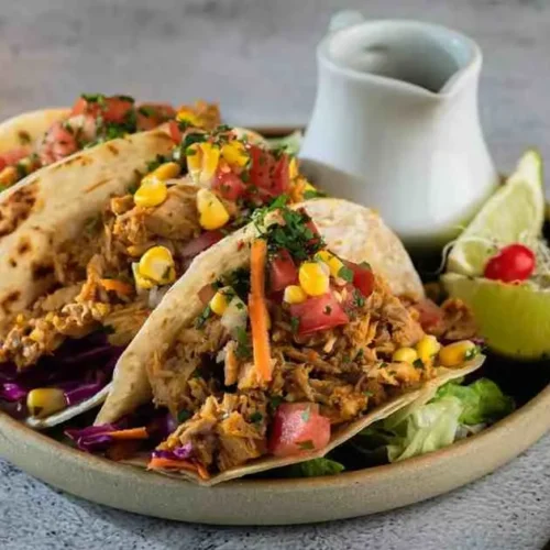 Drizzling BBQ sauce over crockpot pineapple chicken tacos