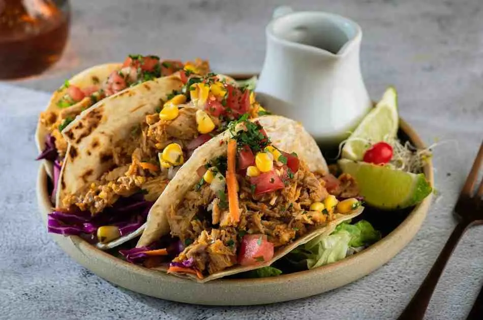 Drizzling BBQ sauce over crockpot pineapple chicken tacos