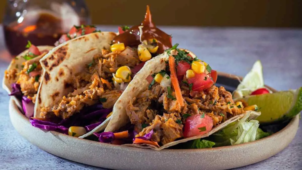 Drizzling BBQ sauce over crockpot pineapple chicken tacos