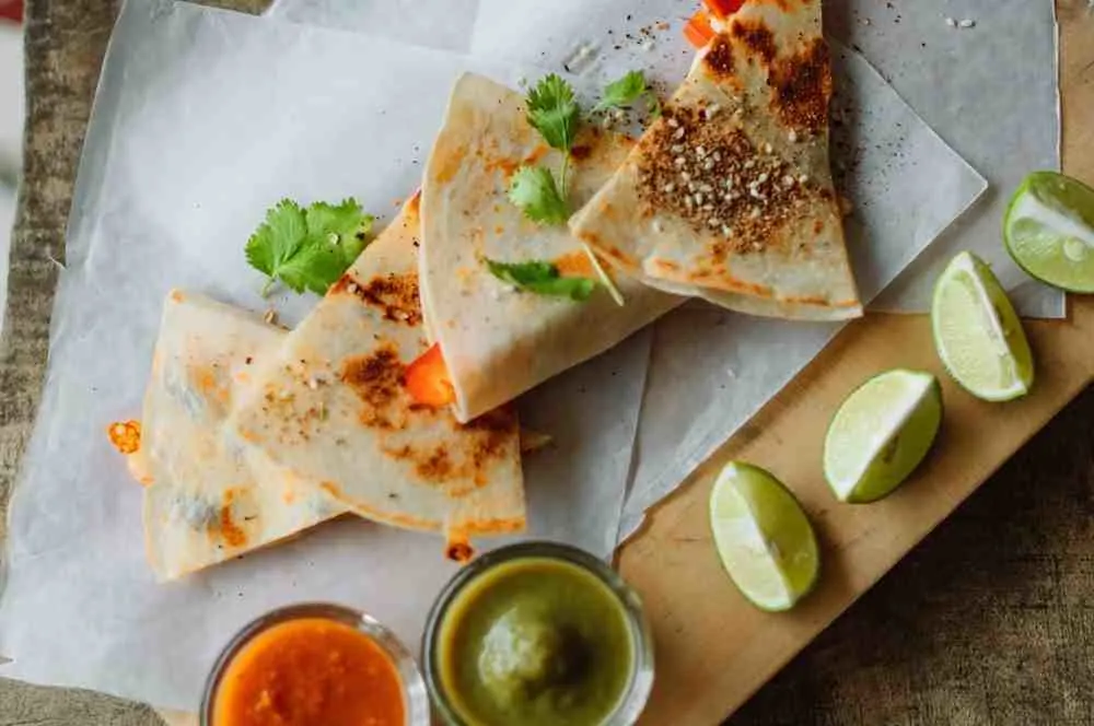 Ground beef quesadilla triangles served with lime wedges and dips