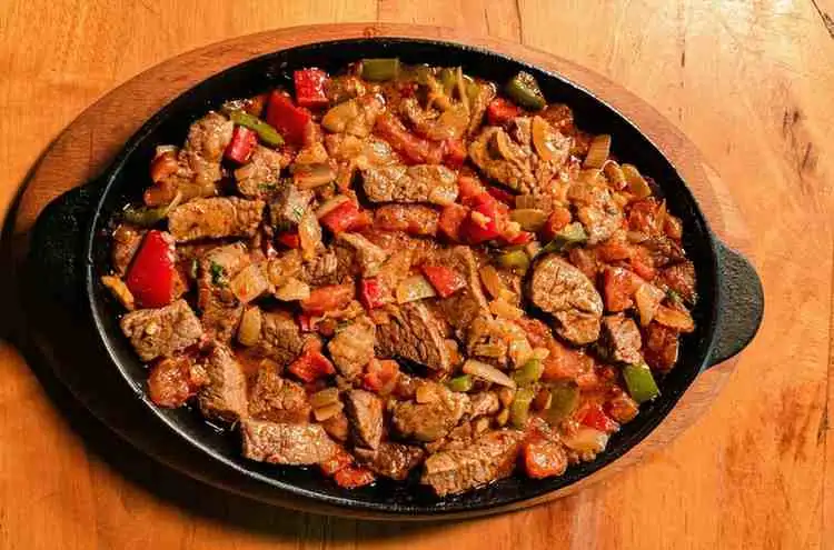 Browning seasoned ground beef with peppers and onions in skillet