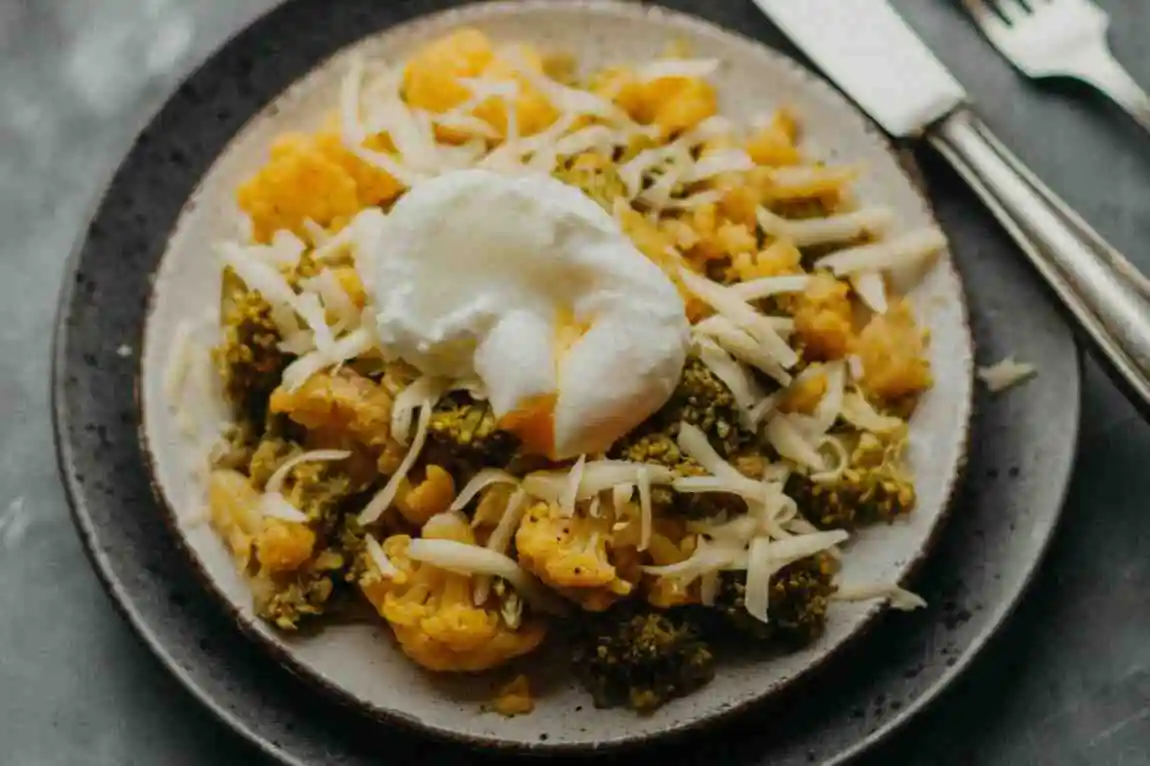 Plated portion of cheesy keto hamburger broccoli skillet topped with melted shredded cheese.