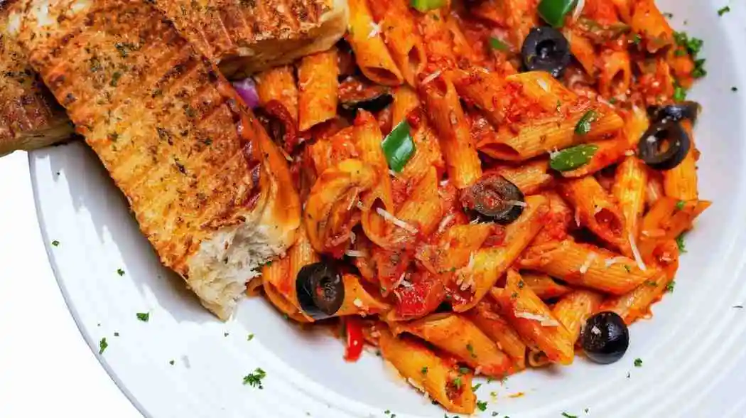 Creamy Italian pasta twirled in a white bowl with garlic bread on the side