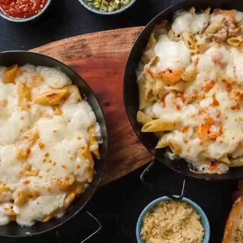 Flat lay of cheesy crockpot keto crack chicken casserole served in pans with dip bowls.