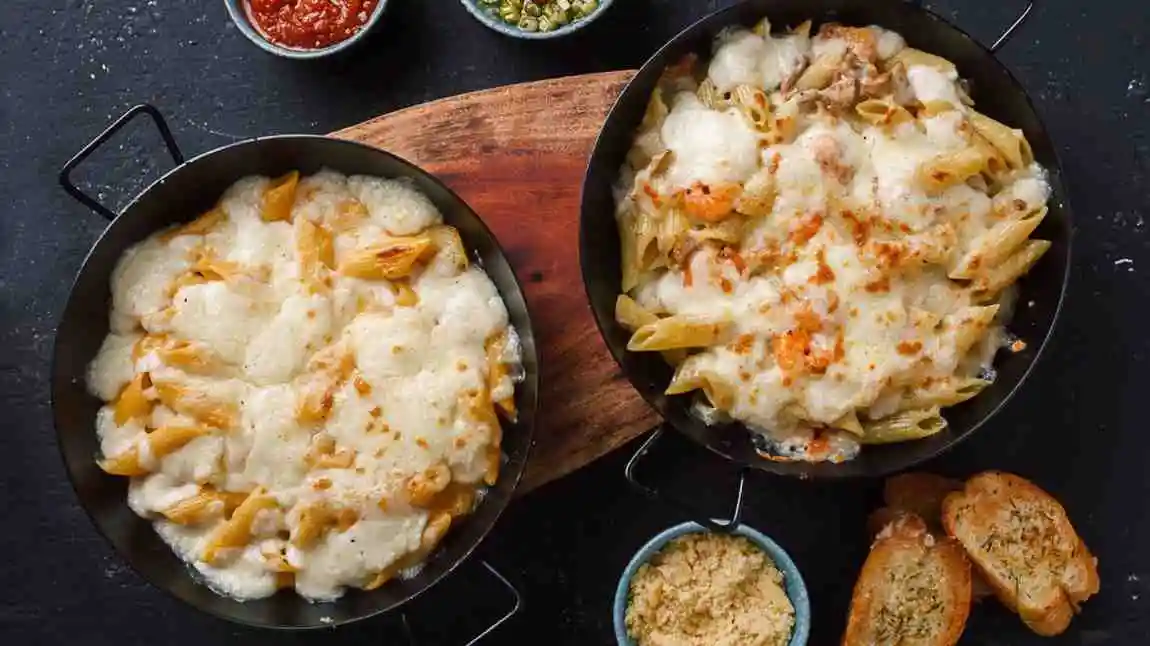 Flat lay of cheesy crockpot keto crack chicken casserole served in pans with dip bowls.