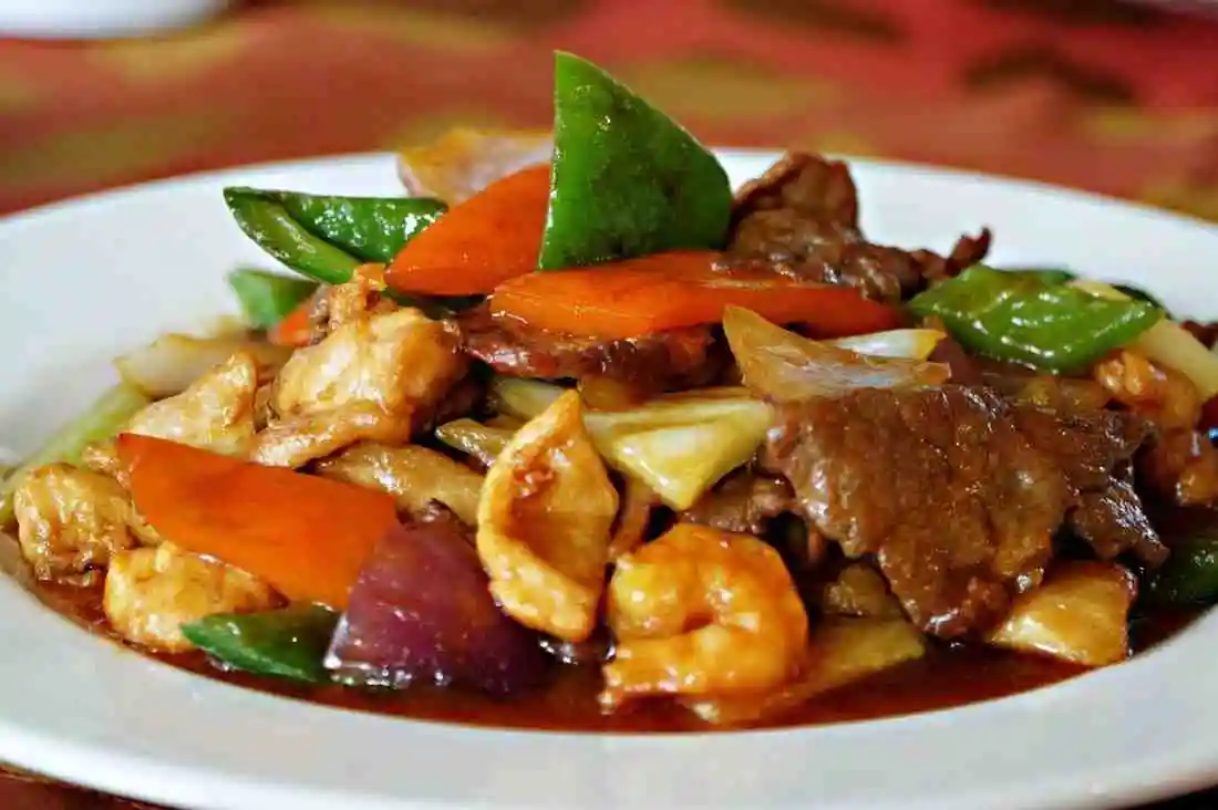 Plated portion of low carb keto steak and shrimp stir fry served on a white plate with fresh vegetables.