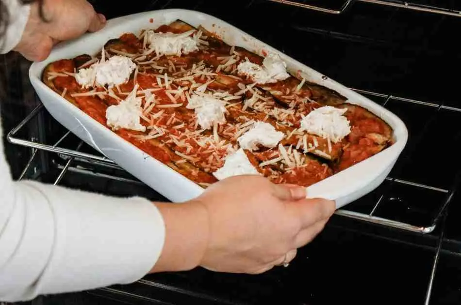 Placing assembled keto pizza casserole into the oven to bake