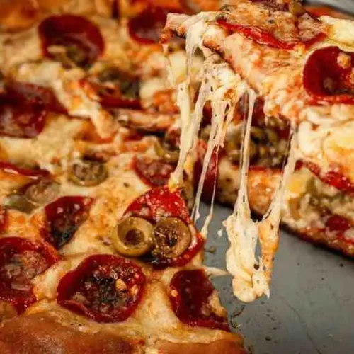 Lifting a slice of cheesy low carb pizza casserole with melted mozzarella and pepperoni