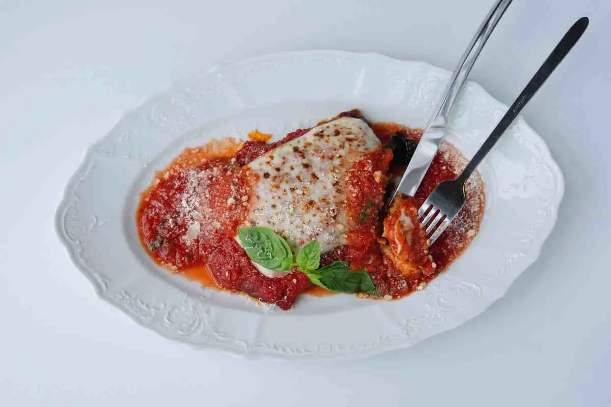 Plated keto chicken parmesan with marinara sauce and melted cheese on a white plate