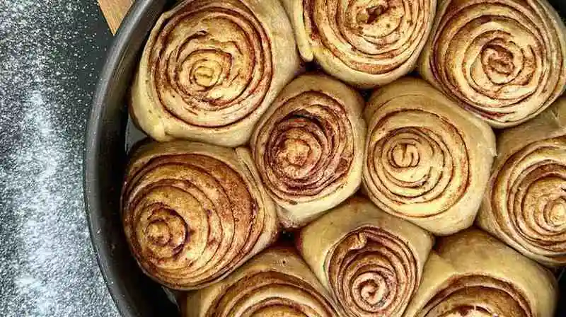 Freshly rolled crescent roll dough cinnamon rolls placed in a round baking pan ready to bake.