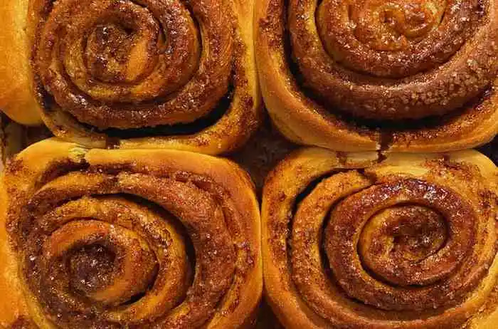 Close up view of golden brown baked cinnamon rolls with swirled brown sugar filling.