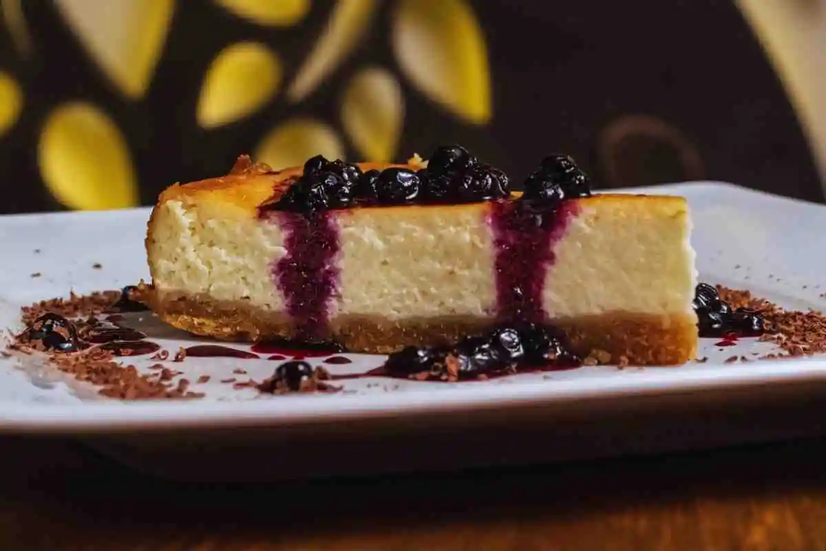 A single slice of blueberry cream cheese bar served on a white plate with blueberry topping.