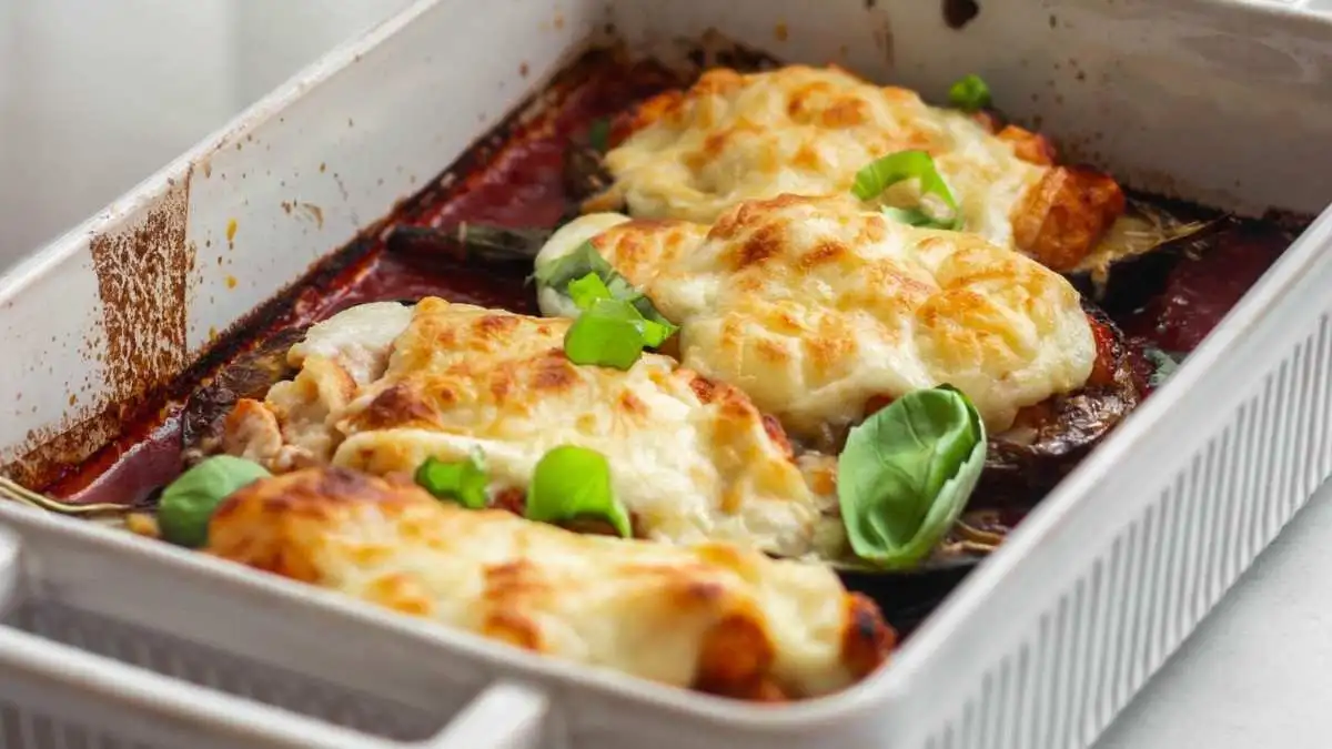 Freshly baked healthy chicken casserole with melted cheese and basil in a ceramic dish