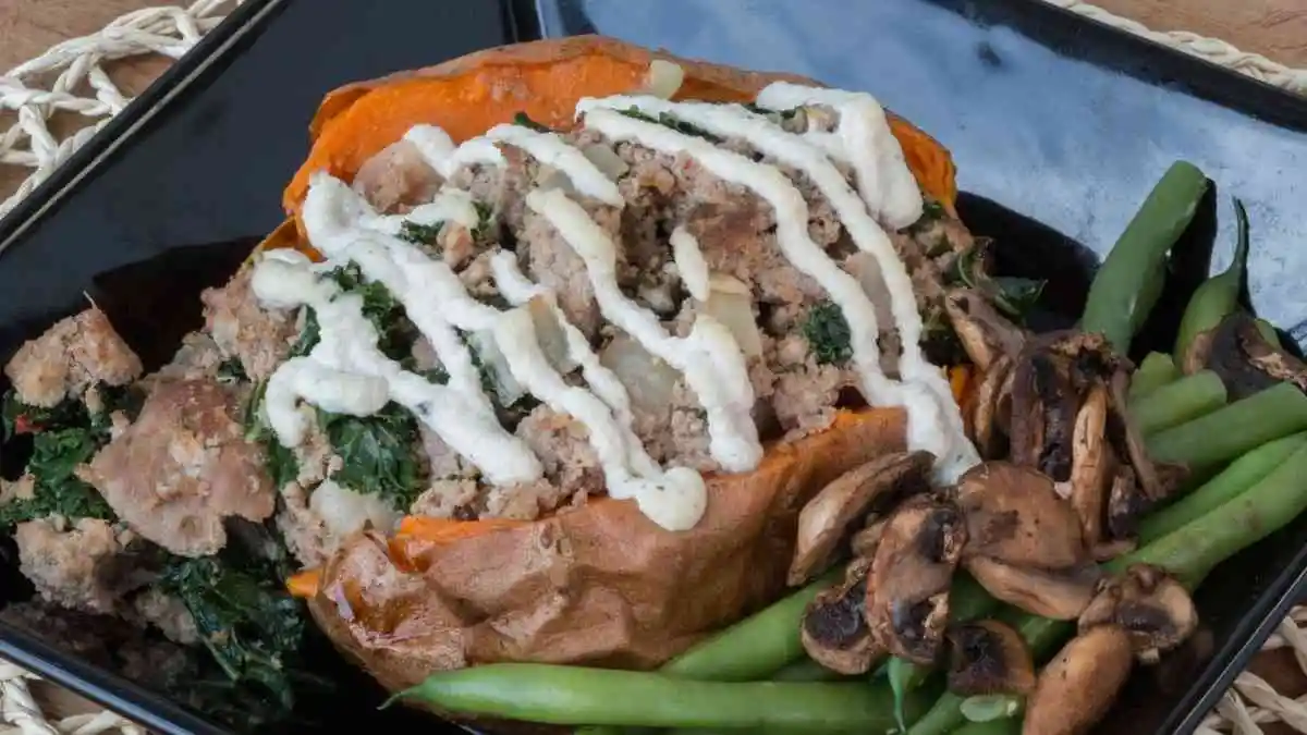 Baked loaded breakfast sweet potato filled with savory toppings and Greek yogurt drizzle